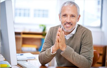 smiling man at desk with hands together